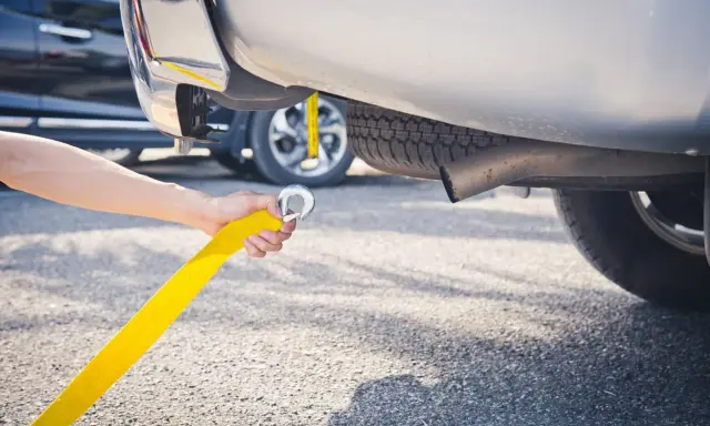 Ręka trzymająca żółtą linę do holowania, przygotowująca do holowania na autostradzie.