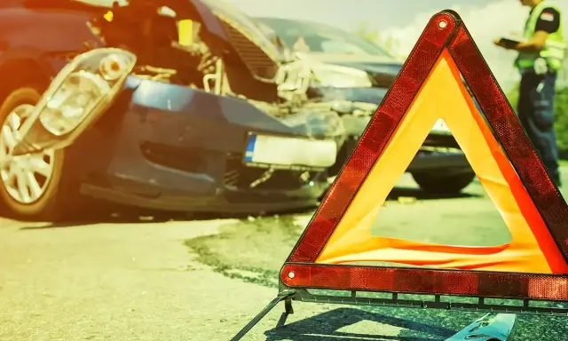 Trójkąt ostrzegawczy i uszkodzony samochód po wypadku. Na drodze widać też funkcjonariusza. To wyposażenie samochodu we Włoszech, które może uratować życie.