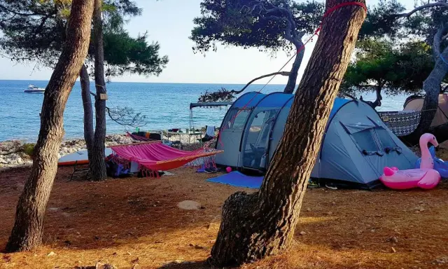 Idealne wakacje: chorwacja pod namiotem, z hamakiem, dmuchanym flamingiem i widokiem na morze.
