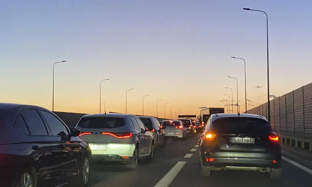 Korek na trasie Kraków - Poznań jak najszybciej. Samochody stoją na autostradzie o zachodzie słońca.