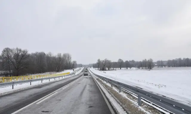 Zimowa trasa, śnieg przy drodze, drzewa bez liści. Nowy tomyśl trasa wita podróżnych.