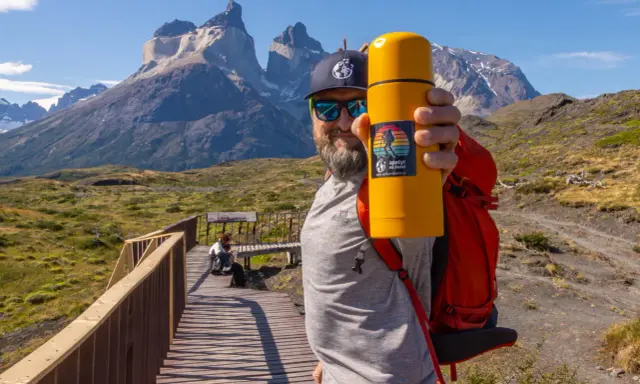 Mężczyzna z żółtym termosem na tle majestatycznych gór. To z pewnością Patagonia, a nie Alzacja.