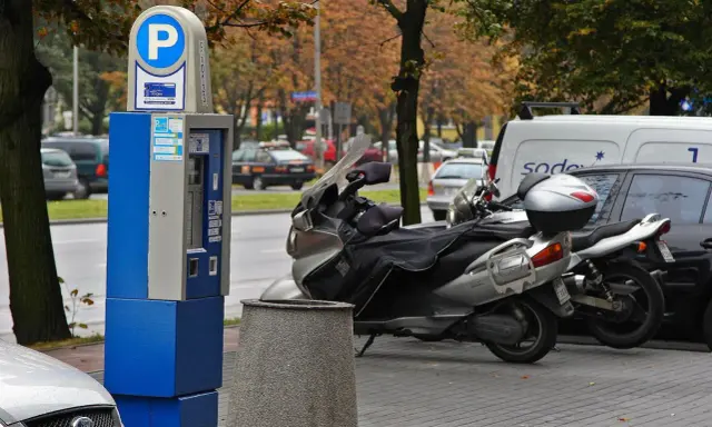 Parkomat z symbolem "P" i skuterem obok. Upewnij się, że masz ważny bilet, by uniknąć mandatu za parkowanie.