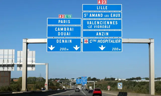 Znaki drogowe na autostradzie we Francji wskazują drogę do Lille, Paryża, Cambrai, Douai i Denain.