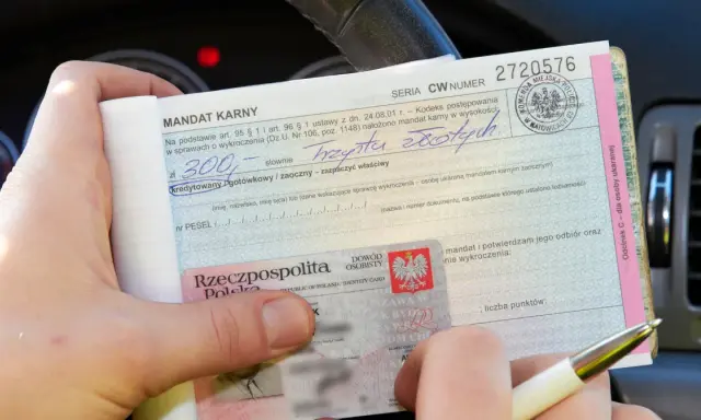 Ręka trzyma mandat karny na kwotę 300 zł. Obok dowód osobisty. Jak uniknąć mandatu? Uważaj na drodze!