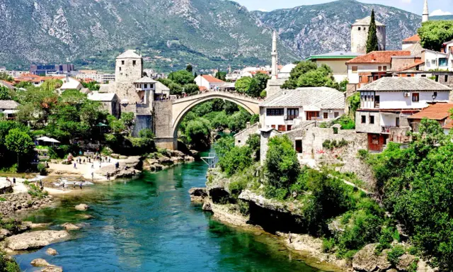Mostar, Bośnia i Hercegowina: zielona karta dla turystów. Stary Most i rzeka Neretwa w letnim słońcu.