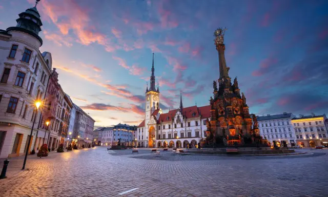 Rynek w Ołomuńcu, perle Moraw Południowych, o zachodzie słońca. Majestatyczna kolumna Trójcy Świętej i ratusz w blasku lamp.
