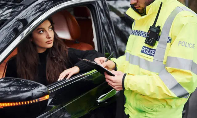 Policjant spisuje mandat młodej kobiecie w samochodzie. Pamiętaj, czego nie robić na Węgrzech, by uniknąć takich sytuacji.