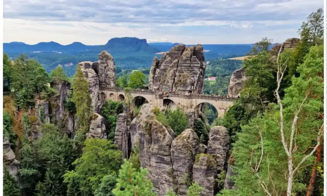 Kamienny most Basteibrücke w Szwajcarskiej Saksonii, łączący skalne baszty pośród zielonych lasów i gór.