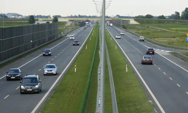 Różne rodzaje dróg: autostrada z pasami ruchu, barierkami i ekranami akustycznymi. Samochody poruszają się po jezdni.