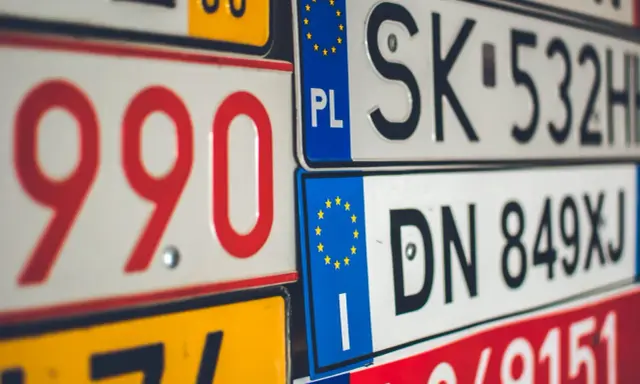Stos tablic rejestracyjnych, w tym polskie z symbolem PL i europejską gwiazdką. Widać numery takie jak 990, SK 532HH, DN 849XJ.