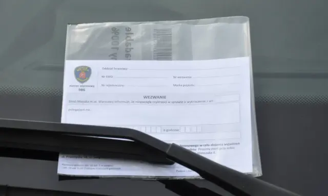 Wezwanie od Straży Miejskiej za złe parkowanie. Dokument zawiera pieczęć Straży Miejskiej Warszawa, numer alarmowy 986 i pole do wpisania przyczyny wezwania.