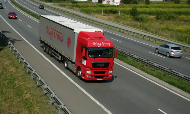 Czerwony tir Magtrans jedzie autostradą. Kierowca może otrzymać mandat za wyprzedzanie tirem w niewłaściwym miejscu.