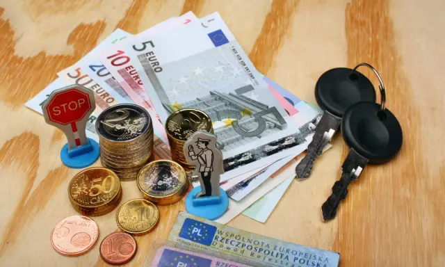 Kluczyki, pieniądze i figurka policjanta sugerują potencjalne mandaty w Niemczech.