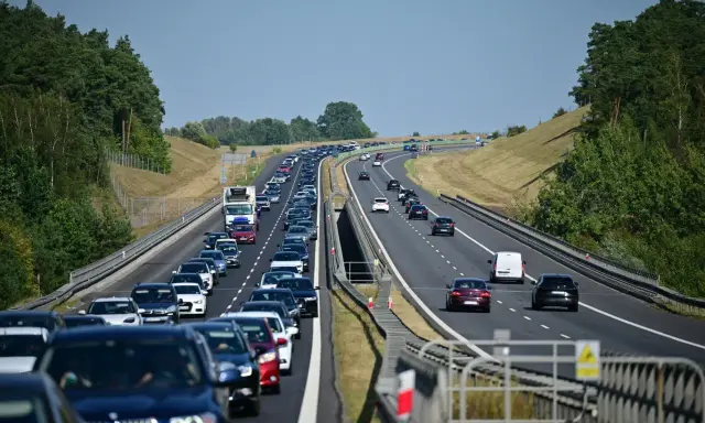 Korek samochodów na autostradzie A1, zieleń po bokach, błękitne niebo.