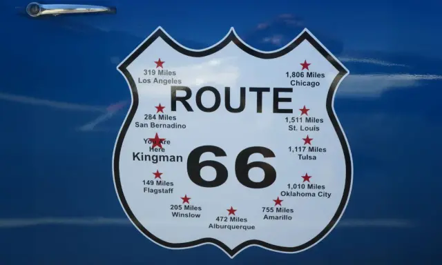 Tablica z napisem "ROUTE 66" i odległościami do miast, w tym "You Are Here Kingman".