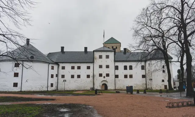 Biały zamek z wieżą i zielonym dachem, symbol najstarszego miasta w Finlandii.