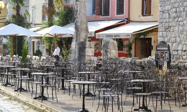 Letni dzień na półwyspie Istria. Pusta kawiarnia z czarnymi, metalowymi stolikami i krzesłami czeka na gości.