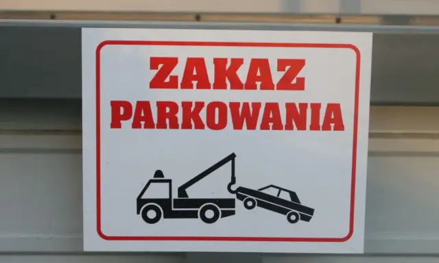 Zasady parkowania na parkingu: zakaz parkowania, holowanie pojazdów. Znak ostrzega przed odholowaniem źle zaparkowanego auta.