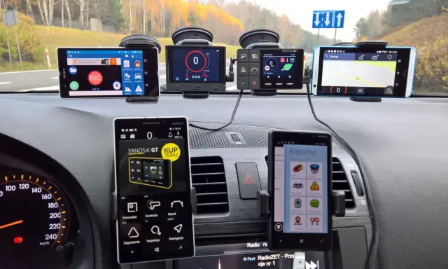 Na desce rozdzielczej samochodu zamontowano kilka urządzeń nawigacyjnych i telefonów, które pomagają w podróży. Widać prędkościomierz i mapę. Ta piła trasa była dobrze przygotowana.
