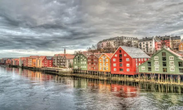Kolorowe domy na palach wzdłuż rzeki, przypominające malownicze trondheim fiordy.