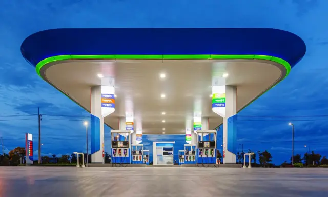 Stacja paliw z podświetlanym zadaszeniem i dystrybutorami. Widoczne ceny paliw, np. Diesel B10, Gasohol 95, E20.