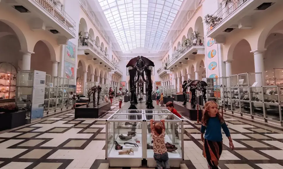 Dzieci zwiedzają Muzeum Ewolucji PAN, jedno z najciekawszych muzeów w Warszawie, podziwiając szkielet mamuta.