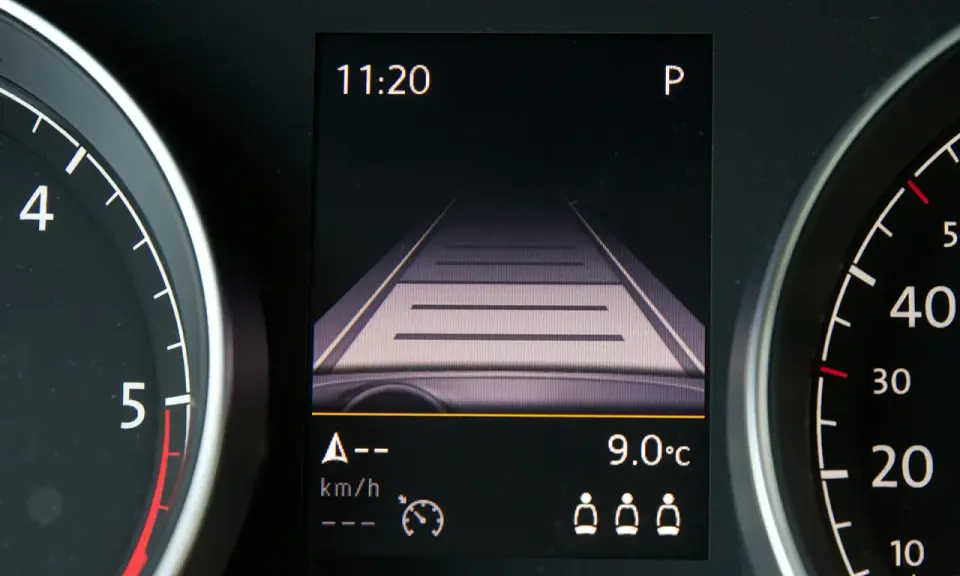 Wyświetlacz w samochodzie pokazuje widok drogi, zegar 11:20 i temperaturę 9°C. To pomocne informacje, gdy zastanawiasz się, tempomat co to jest i jak działa.