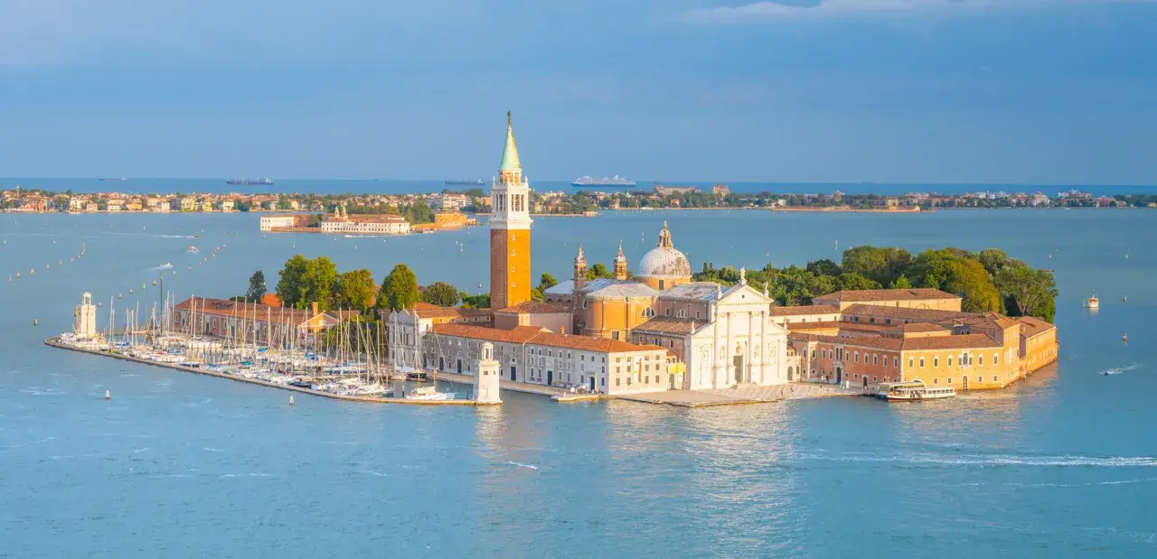 Wyspy laguny weneckiej: San Giorgio Maggiore z dzwonnicą i kościołem, otoczona wodą i łodziami.