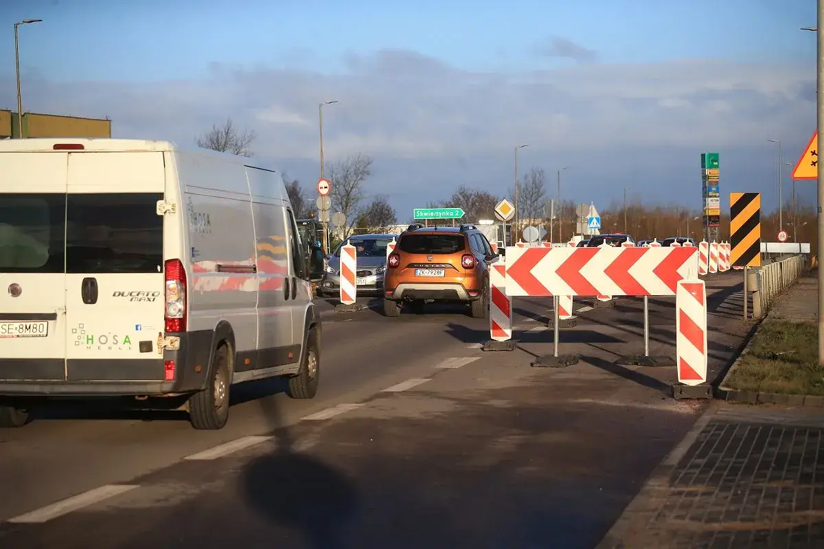 Korki na trasie do Władysławowa. Pomarańczowy SUV i biały bus stoją w kolejce za barierami drogowymi.