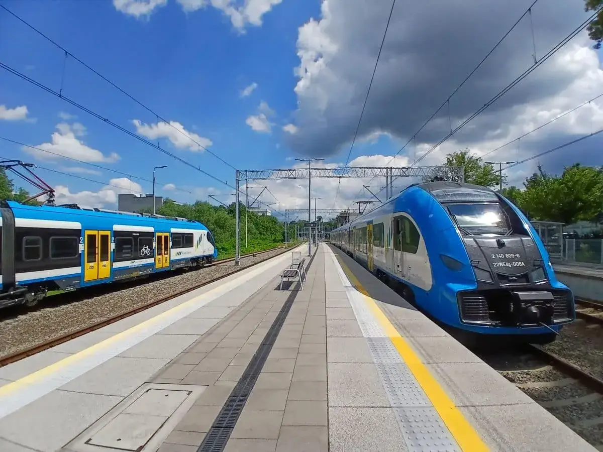 Dwa niebiesko-białe pociągi stoją na stacji, gotowe do podróży. Może to najszybsza trasa do Kielc?