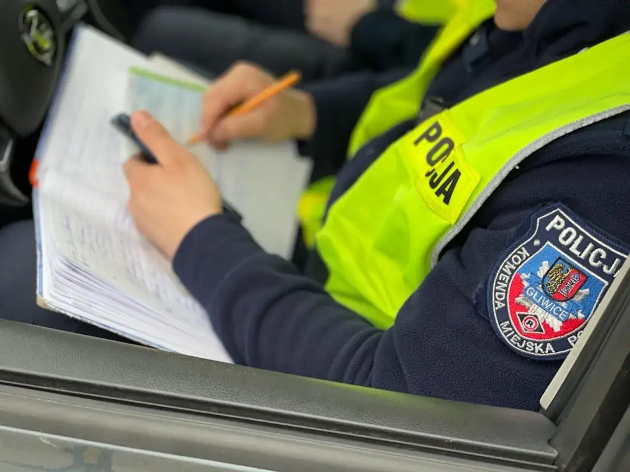 Policjantka w kamizelce odblaskowej spisuje notatki. Za niezachowanie bezpiecznej odległości grozi mandat.