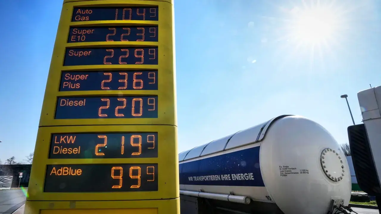 Ceny paliw w Niemczech na tablicy stacji: Auto Gas 1.049, Super E10 2.239, Super 2.299, Super Plus 2.369, Diesel 2.209, LKW Diesel 2.199, AdBlue 0.999. Obok cysterna.