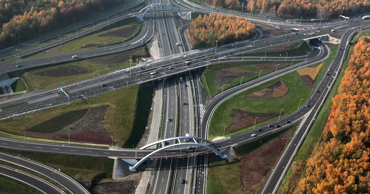 Rozległy węzeł drogowy na autostradzie A4, z licznymi pasami ruchu, wiaduktami i łukami, otoczony jesienną zielenią i drzewami.