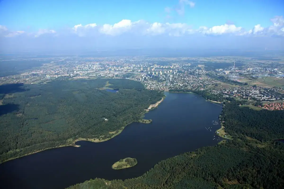 Widok z lotu ptaka na jezioro i lasy otaczające miasto. Tychy, co warto zobaczyć, to z pewnością malownicze krajobrazy i bliskość natury.