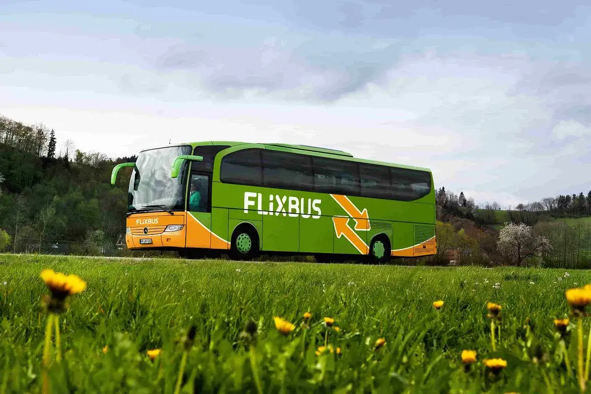 Zielona zielona trasa Flixbus z Kielc do Zakopanego, przejeżdża przez malownicze krajobrazy z żółtymi kwiatami na pierwszym planie.