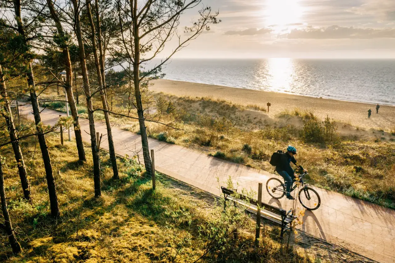 Rowerzysta na ścieżce wzdłuż plaży w Sarbinowie. Słońce odbija się od morza, tworząc malowniczą trasę.