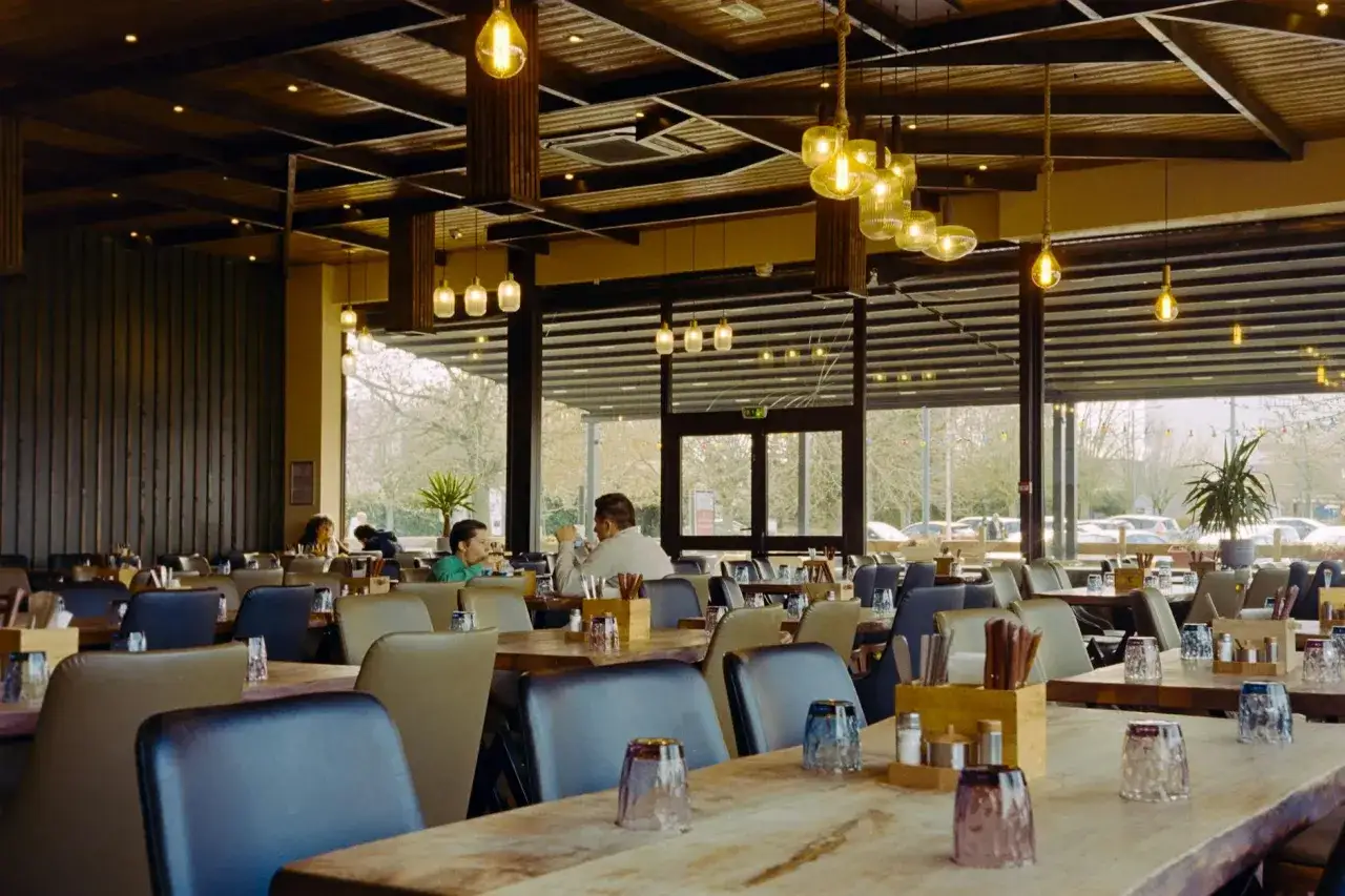 Przytulna restauracja z drewnianymi elementami i designerskimi lampami. Idealne miejsce na dobre jedzenie na trasie Kraków-Zakopane.