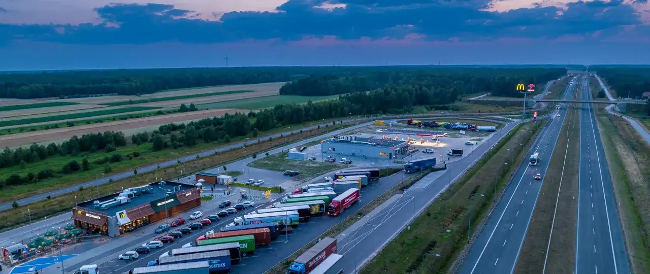 Nocny widok na MOP skrót przy autostradzie z McDonald's, stacją paliw i parkingiem pełnym ciężarówek.
