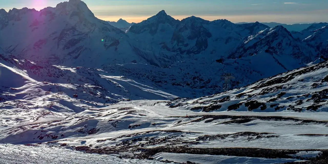 Ośnieżone szczyty Alp o zachodzie słońca, z widocznymi wyciągami i narciarzami. Krajobraz Les Deux Alpes zapiera dech w piersiach.