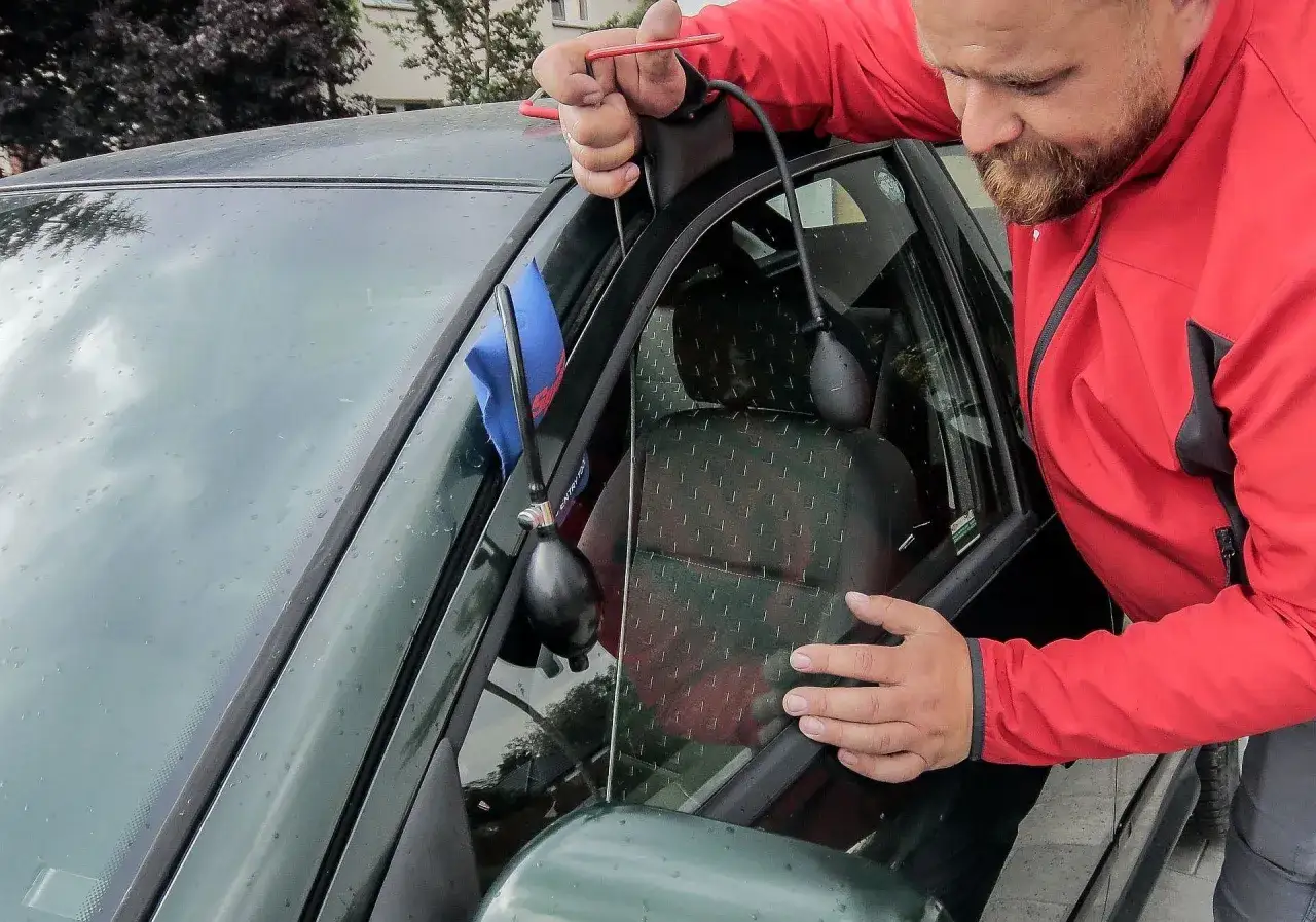 Mężczyzna używa narzędzia do otwierania drzwi, gdy zatrzaśnięte kluczyki w samochodzie jak otworzyć.