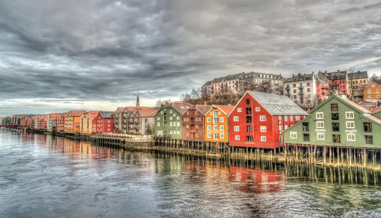 Kolorowe domy na palach wzdłuż rzeki, przypominające malownicze trondheim fiordy.