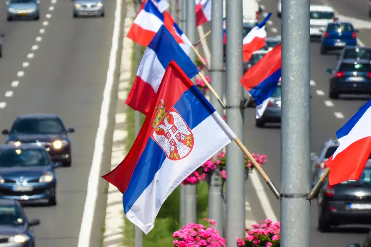 Flagi Serbii i Francji powiewają na wietrze, witając podróżnych na wjeździe do Serbii.