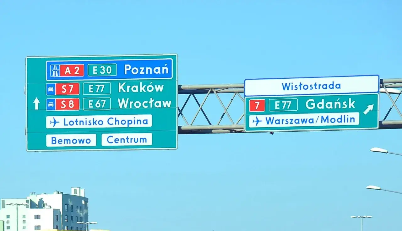 Znaki drogowe wskazują oznaczenie drogi wojewódzkiej S7, S8, A2, E30, E77, E67 do Poznania, Krakowa, Wrocławia, Lotniska Chopina, Bemowa, Centrum, Wistostrada, Gdańska i Warszawy/Modlina.
