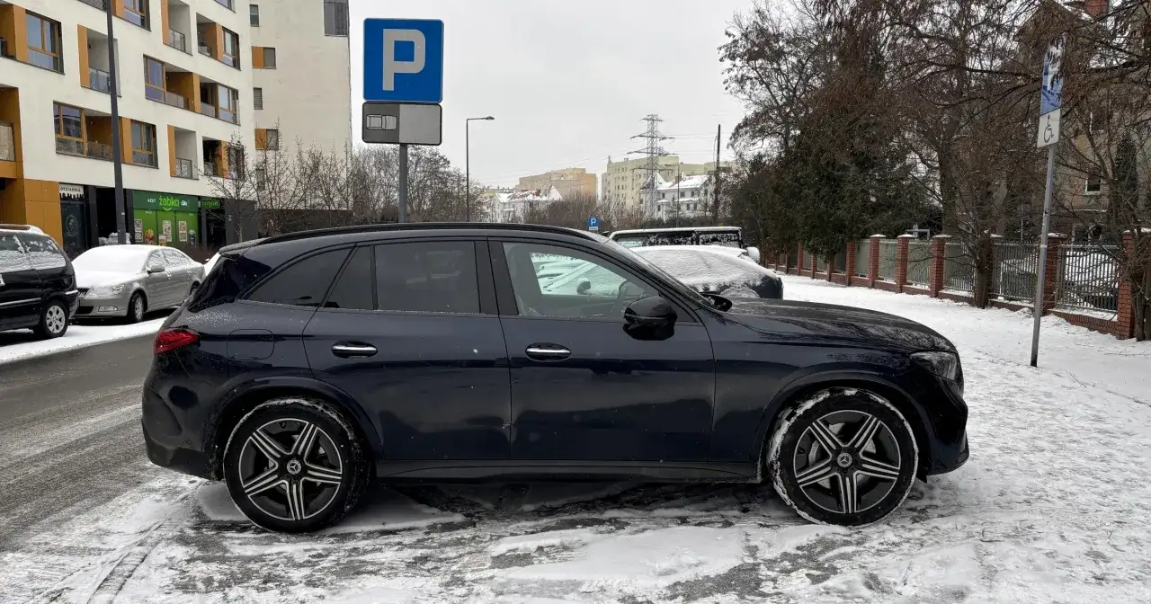 Ciemny Mercedes zaparkowany na śniegu, obok znak
