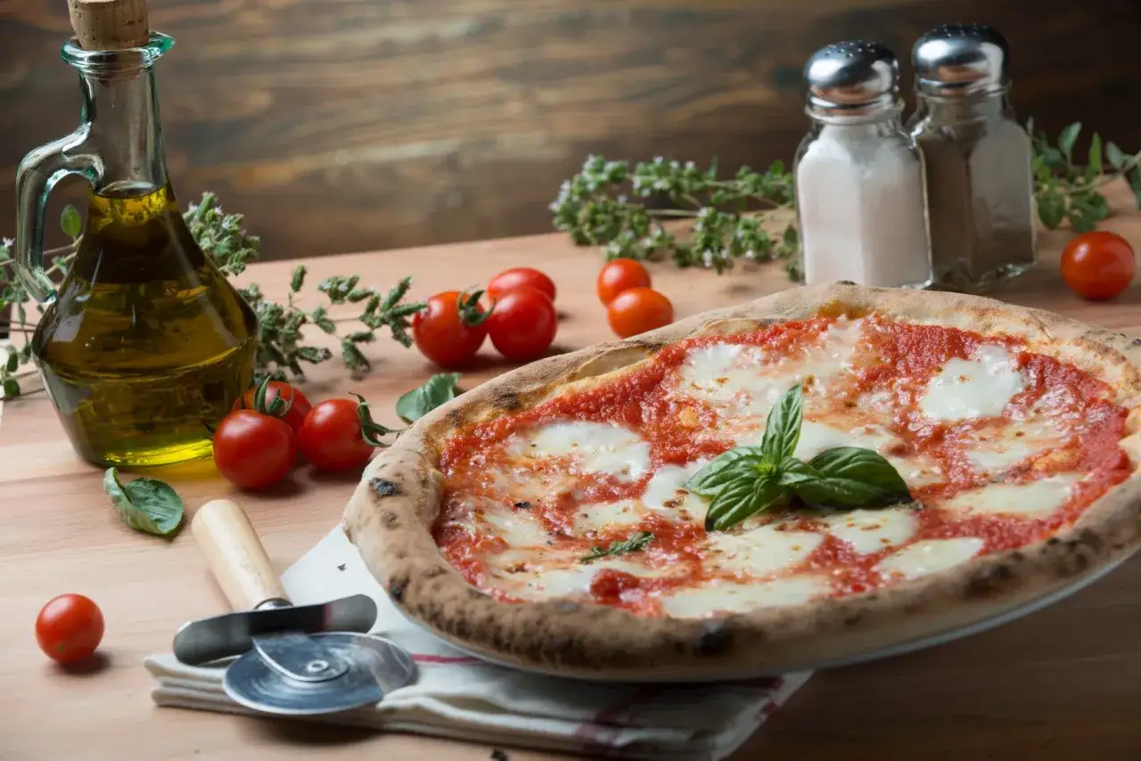 Pyszna pizza Margherita z pomidorkami, bazylią i oliwą. Idealna odpowiedź na pytanie: co zjeść we Włoszech.