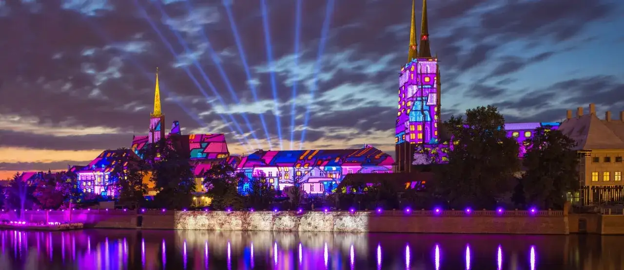 Ostrów Tumski we Wrocławiu nocą, iluminowany kolorowymi projekcjami. Warto zobaczyć to widowisko!