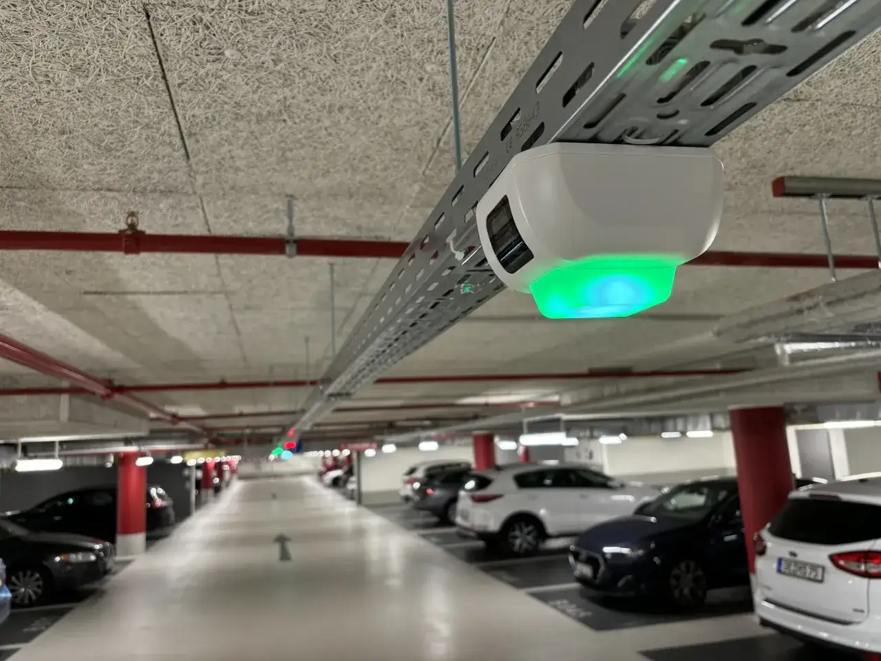Czujnik parkowania z zielonym światłem na trasie w Lipsku. Pod sufitem widoczne rury i instalacje.