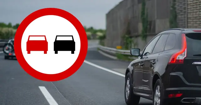 Znak zakazu wyprzedzania z prawej strony. Czarny SUV jedzie po drodze, a z lewej strony widać znak drogowy.