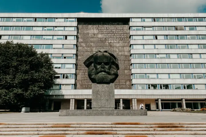Pomnik Karola Marksa w Chemnitz, jedna z głównych atrakcji miasta, na tle modernistycznego budynku.